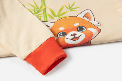 Close-up of a beige garment sleeve with a bright orange-red cuff and a printed cartoon red panda face with green bamboo on the body.